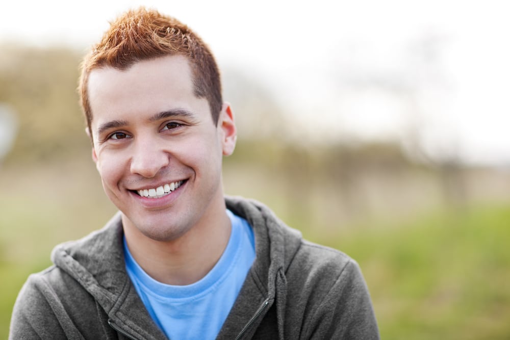 A shot of a mixed race man smiling outside